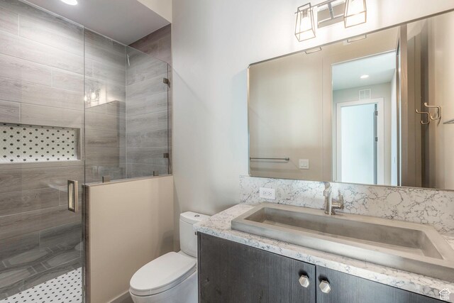 bathroom featuring vanity, toilet, and a shower with door