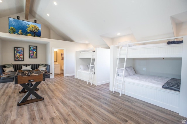 bedroom with lofted ceiling with beams, wood-type flooring, and connected bathroom