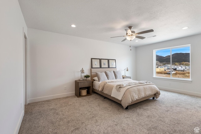 carpeted bedroom featuring ceiling fan and a textured ceiling