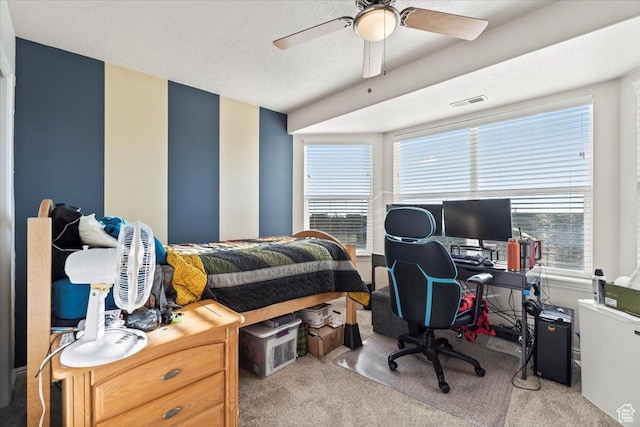 carpeted bedroom featuring visible vents, a ceiling fan, and a textured ceiling