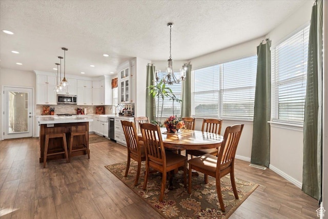 dining area featuring light wood finished floors, a textured ceiling, and an inviting chandelier