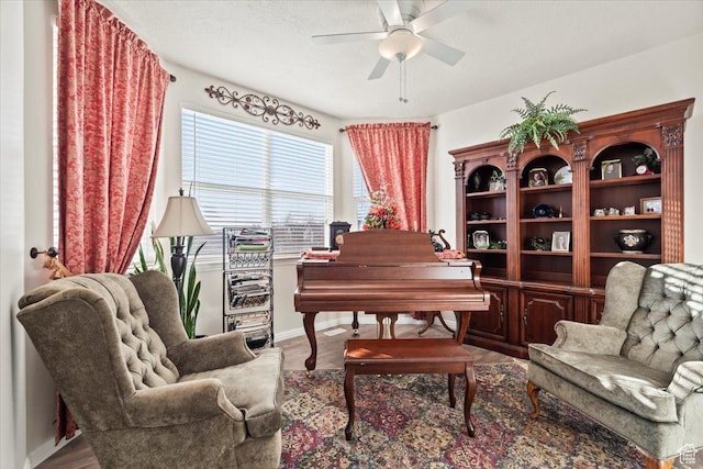 living area featuring baseboards, a ceiling fan, and wood finished floors