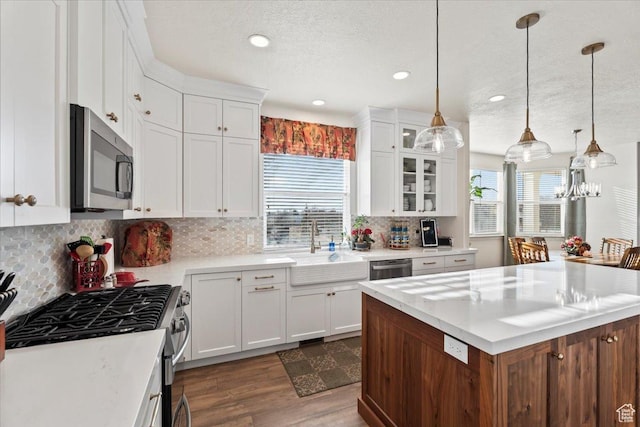 kitchen with dark wood-style flooring, light countertops, white cabinetry, and appliances with stainless steel finishes