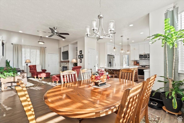 dining area featuring a wealth of natural light, wood finished floors, and ceiling fan with notable chandelier