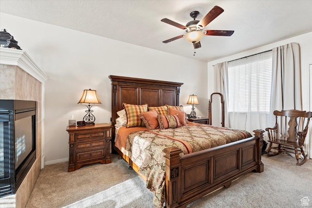 bedroom featuring ceiling fan, a tile fireplace, and light carpet
