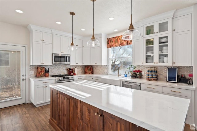 kitchen with white cabinets, a center island, appliances with stainless steel finishes, dark wood-style flooring, and a sink
