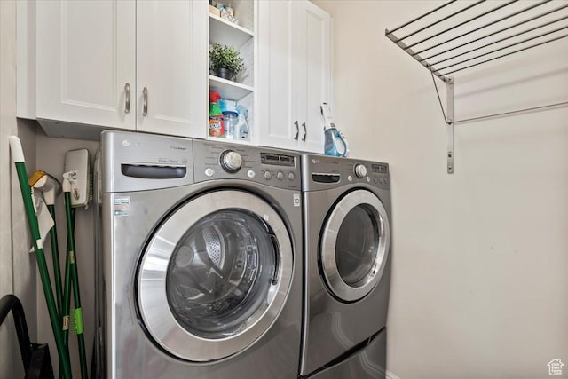 clothes washing area featuring cabinet space and washing machine and clothes dryer