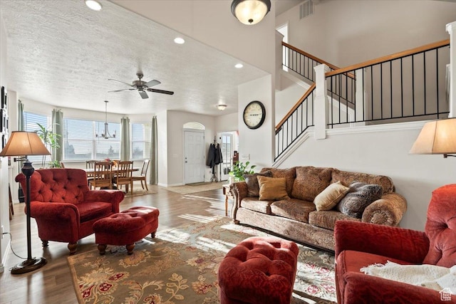 living area featuring stairway, visible vents, a ceiling fan, and wood finished floors
