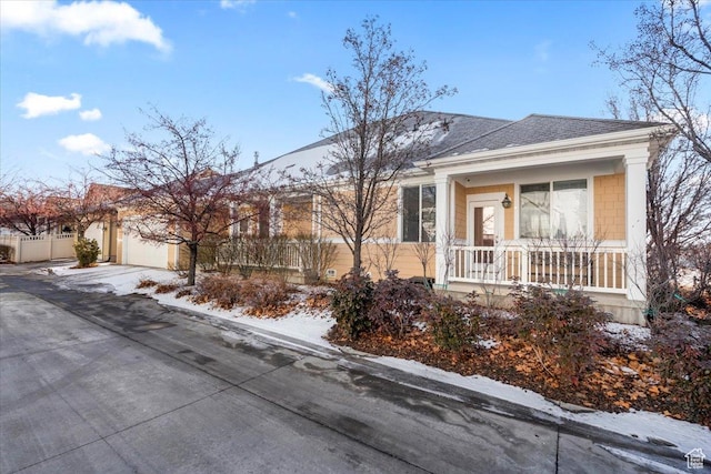 view of front of home with concrete driveway, fence, a garage, and covered porch