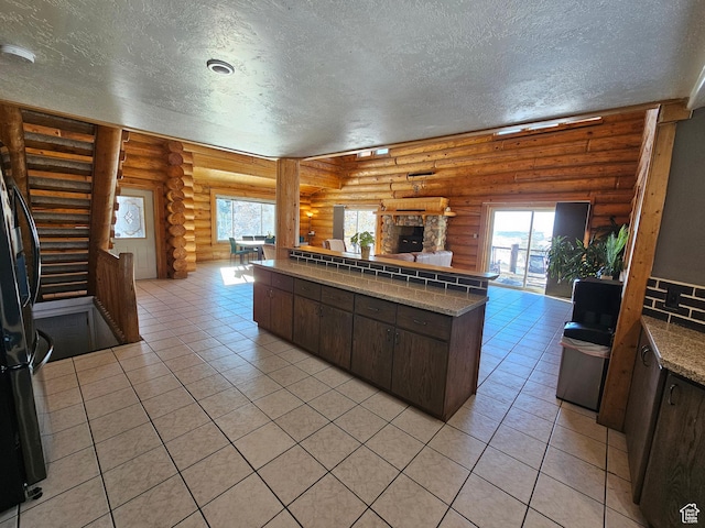 11905 E 24560 N, Fairview, UT 84629 - kitchen featuring dark brown cabinetry, a stone fireplace, rustic walls, and light tile patterned floors