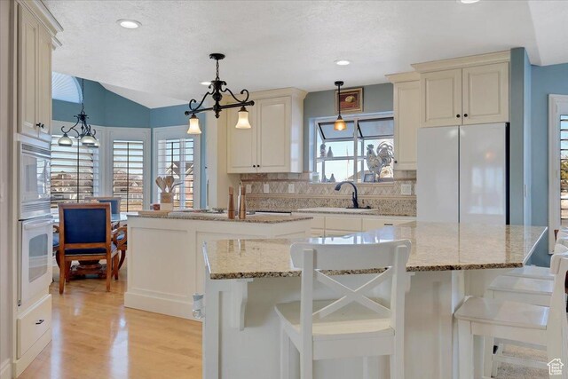 818 Summit Dr, Smithfield, UT 84335 - kitchen with white appliances, a sink, a kitchen island, decorative backsplash, and light wood finished floors