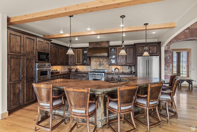 655 W 85 S, Glenwood, UT 84730 - kitchen featuring stainless steel appliances, premium range hood, beamed ceiling, backsplash, and light wood-style flooring