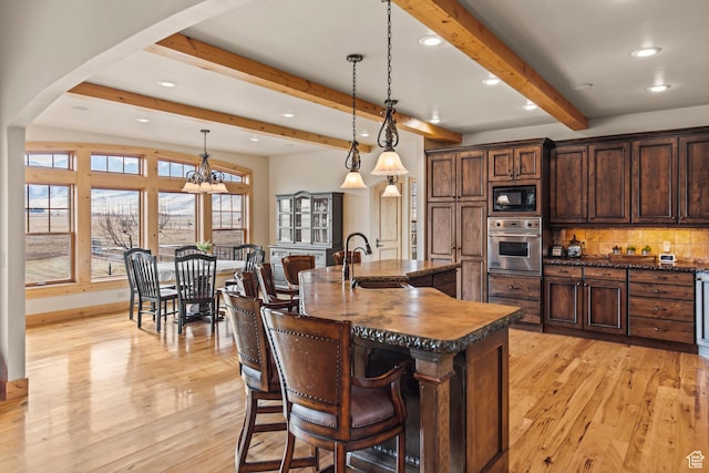 655 W 85 S, Glenwood, UT 84730 - kitchen with oven, black microwave, beam ceiling, light wood-style floors, and a kitchen bar