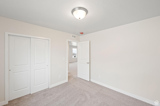 unfurnished bedroom with light carpet and a closet