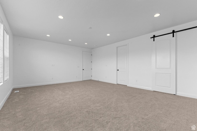 carpeted spare room featuring a barn door