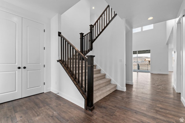 foyer entrance featuring a towering ceiling and dark hardwood / wood-style flooring