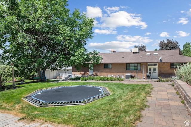 1975 Laguna Vista Dr, Orem, UT 84058 - back of property with a trampoline, brick siding, a lawn, and french doors