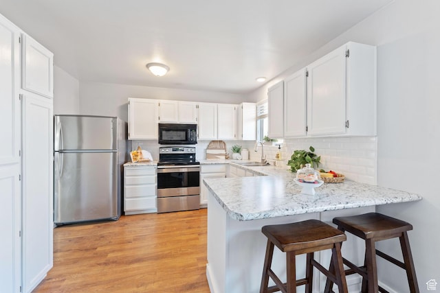 9737 S Stonehaven St, South Jordan, UT 84009 - kitchen featuring white cabinetry, appliances with stainless steel finishes, kitchen peninsula, and light hardwood / wood-style flooring