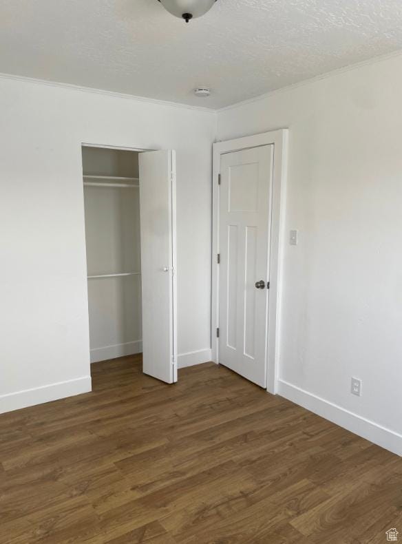 unfurnished bedroom featuring dark hardwood / wood-style flooring, a closet, and a textured ceiling