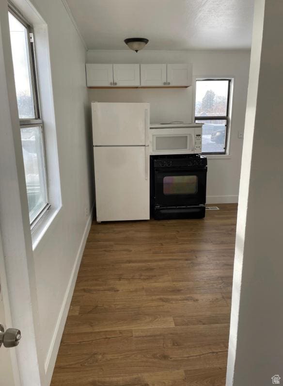 kitchen featuring white cabinetry, white appliances, plenty of natural light, and dark hardwood / wood-style flooring