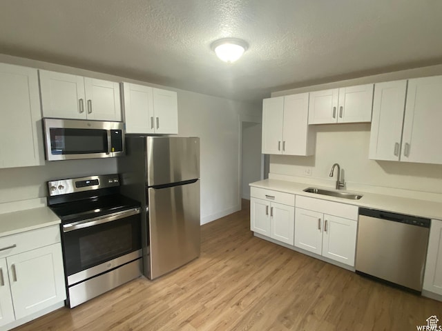 458 E Lambourne Ave, Salt Lake City, UT 84115 - kitchen with sink, white cabinets, stainless steel appliances, a textured ceiling, and light hardwood / wood-style flooring