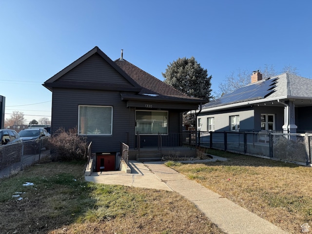 rear view of house with a yard, a patio area, and solar panels