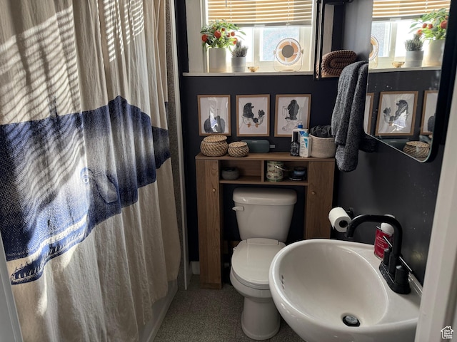 bathroom with a shower with shower curtain, toilet, and sink