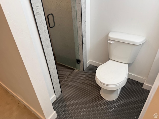 bathroom featuring a shower with shower door and toilet