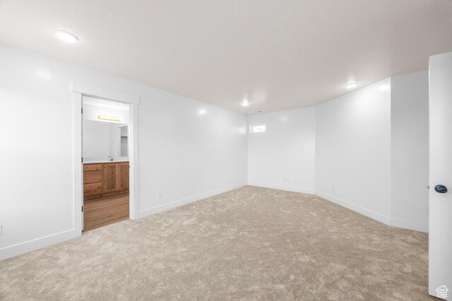 spare room featuring light colored carpet and baseboards