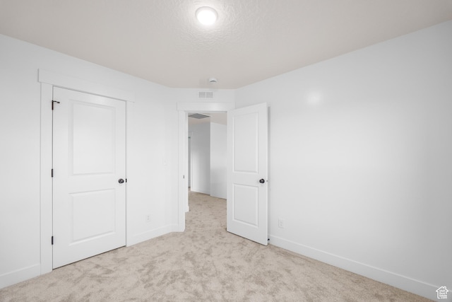 unfurnished bedroom with baseboards, visible vents, and light colored carpet