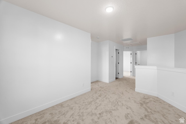 unfurnished room with attic access, light carpet, and baseboards