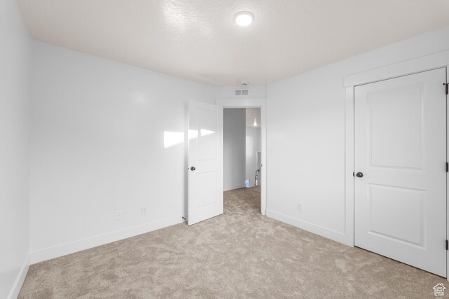 unfurnished bedroom with light carpet, baseboards, visible vents, and a closet