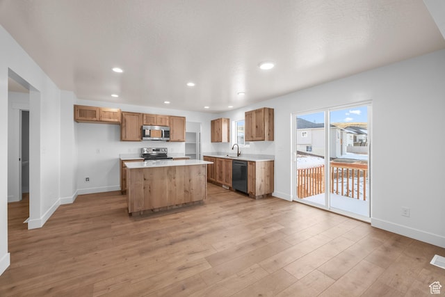 kitchen featuring light countertops, appliances with stainless steel finishes, brown cabinets, and a center island