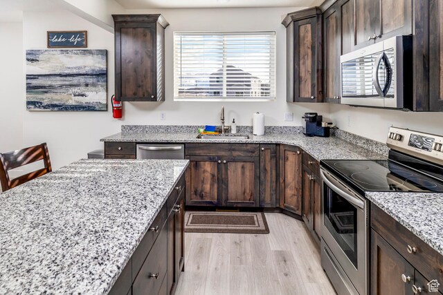 156 E Sailors Way Unit 11, Garden City, UT 84028 - kitchen featuring dark brown cabinetry, sink, light stone countertops, and appliances with stainless steel finishes