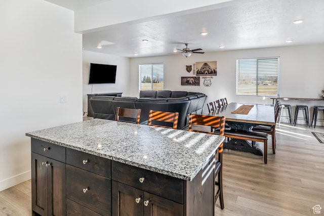 156 E Sailors Way Unit 11, Garden City, UT 84028 - kitchen featuring dark brown cabinets, a kitchen breakfast bar, a center island, light stone countertops, and light wood-type flooring