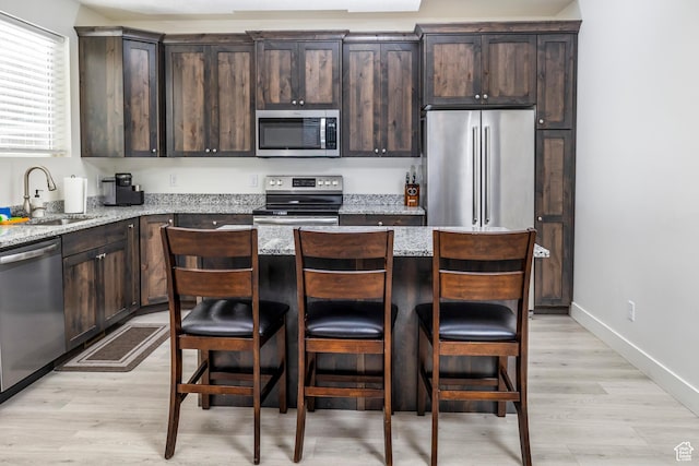 156 E Sailors Way Unit 11, Garden City, UT 84028 - kitchen featuring dark brown cabinetry, appliances with stainless steel finishes, sink, and light stone counters