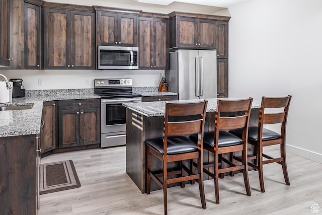 156 E Sailors Way Unit 11, Garden City, UT 84028 - kitchen featuring stainless steel appliances, a kitchen island, light stone countertops, and dark brown cabinets