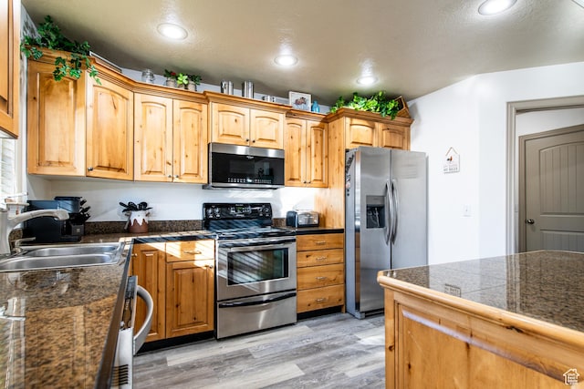 kitchen with sink, stainless steel appliances, and light hardwood / wood-style floors