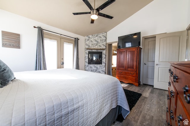 bedroom featuring french doors, a stone fireplace, vaulted ceiling, hardwood / wood-style flooring, and ceiling fan