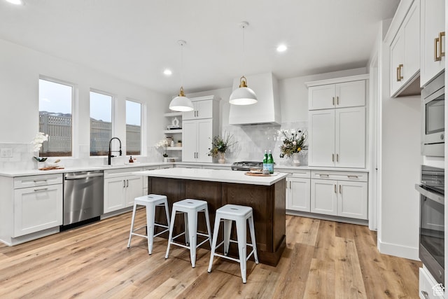 3559 S Garibaldi Way, Saratoga Springs, UT 84045 - kitchen featuring hanging light fixtures, stainless steel appliances, a center island, white cabinets, and light wood-type flooring