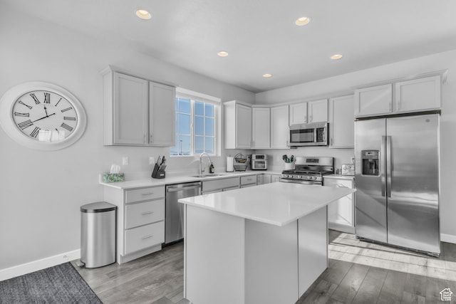 kitchen with a kitchen island, appliances with stainless steel finishes, sink, and light wood-type flooring