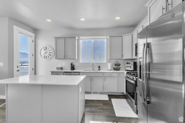 kitchen featuring stainless steel appliances, a center island, sink, and dark hardwood / wood-style flooring