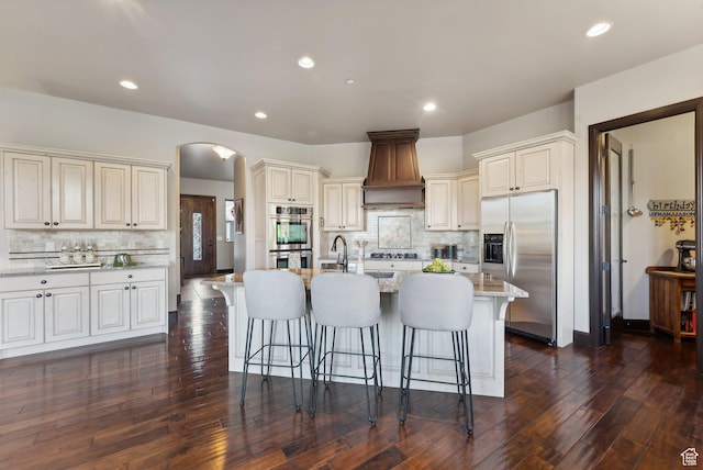 3180 E Stoney Creek Cir S, Heber City, UT 84032 - kitchen with stainless steel appliances, custom exhaust hood, backsplash, arched walkways, and a kitchen breakfast bar