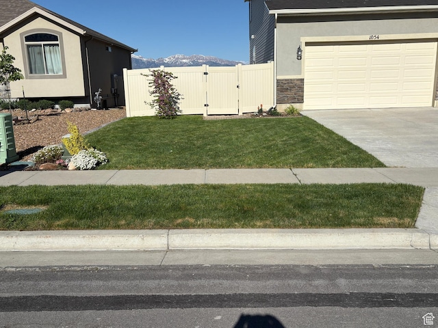 1054 S 1050 W, Tooele, UT 84074 - view of property exterior featuring a gate, driveway, stone siding, an attached garage, and a mountain view