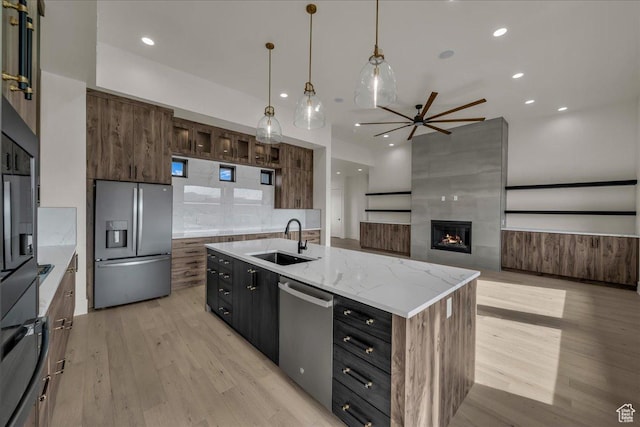 5367 W 3180 S, Hurricane, UT 84737 - kitchen featuring sink, light hardwood / wood-style flooring, an island with sink, a tile fireplace, and stainless steel appliances
