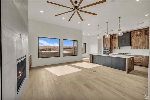 5367 W 3180 S, Hurricane, UT 84737 - kitchen with built in microwave, hanging light fixtures, light wood-type flooring, a large island with sink, and a large fireplace