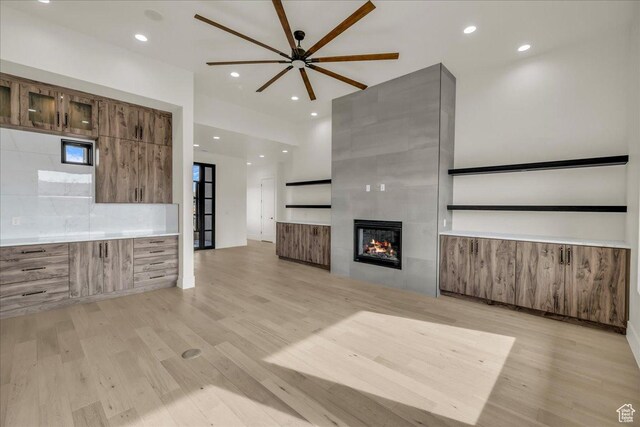 5367 W 3180 S, Hurricane, UT 84737 - unfurnished living room featuring a tiled fireplace, ceiling fan, and light hardwood / wood-style floors