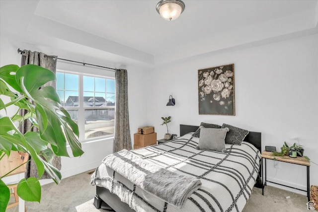 carpeted bedroom featuring a tray ceiling and baseboards