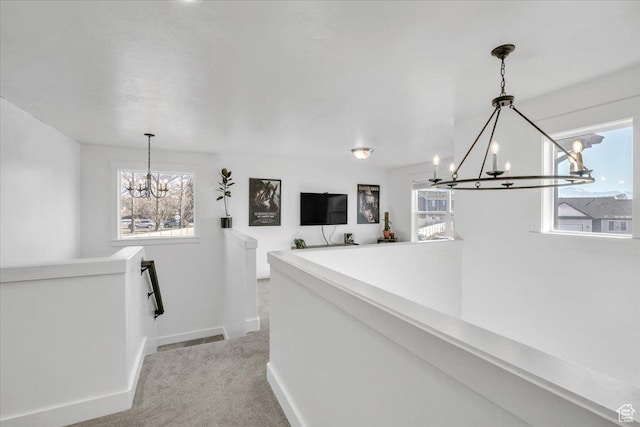 corridor with a notable chandelier, an upstairs landing, and plenty of natural light