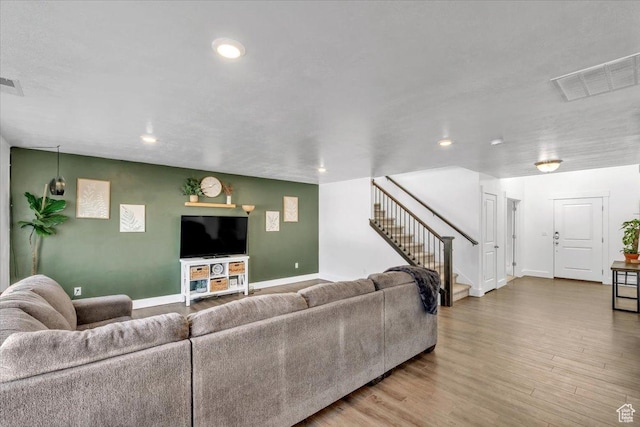 living area with visible vents, wood finished floors, recessed lighting, baseboards, and stairs